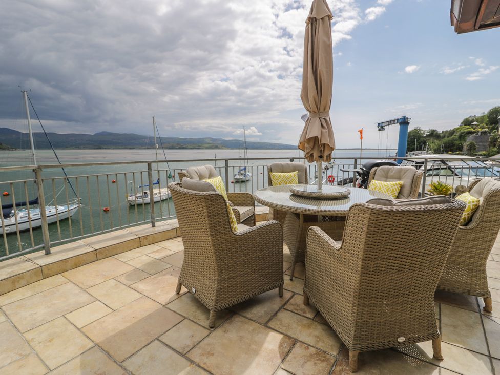 An outdoor area with a table and chairs overlooking water at The Boat Yard Apartment in Porthmadog