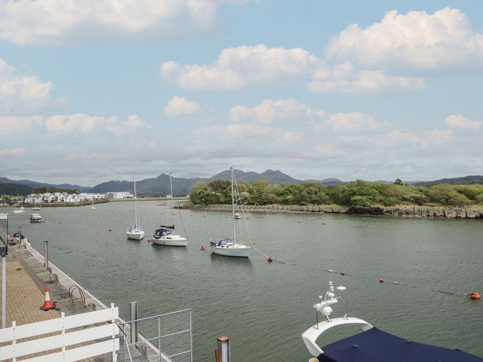 A view of boats on water with mountains in the background at The Boat Yard Apartment Porthmadog