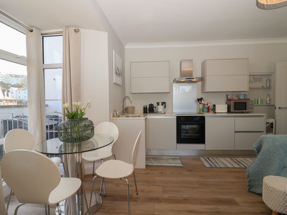 A kitchen with a glass table and chairs at 3 The Elms Salcombe