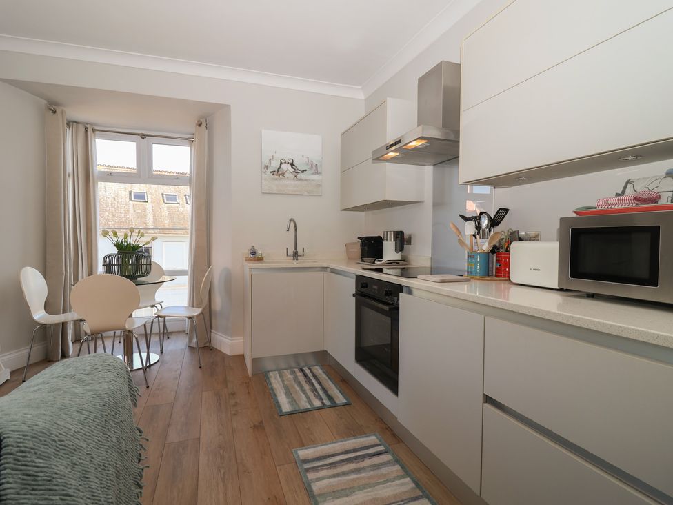 A kitchen with appliances and seating area at 3 The Elms in Salcombe