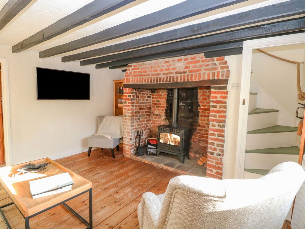 A living room with a fireplace and wood stove at Vintner's Cottage in Reedham
