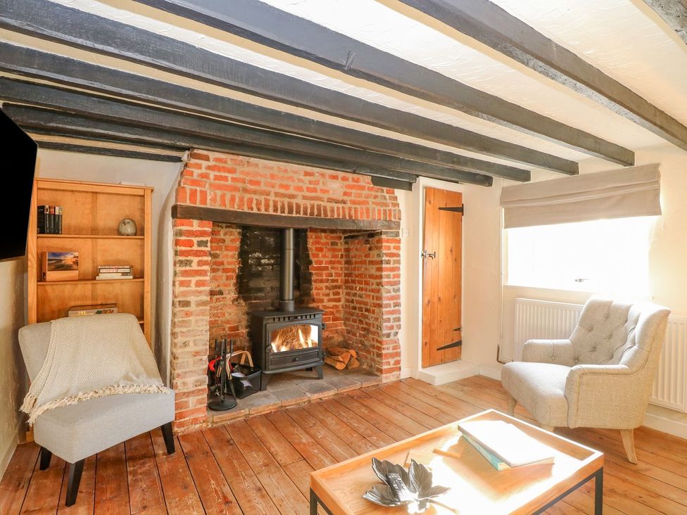 A living room with a fireplace and seating at Vintner's Cottage in Reedham