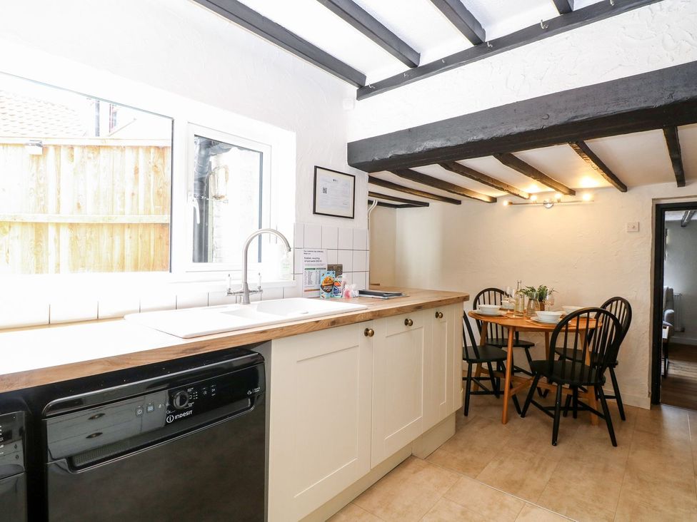 A kitchen with a sink and dining table at Vintner's Cottage in Reedham
