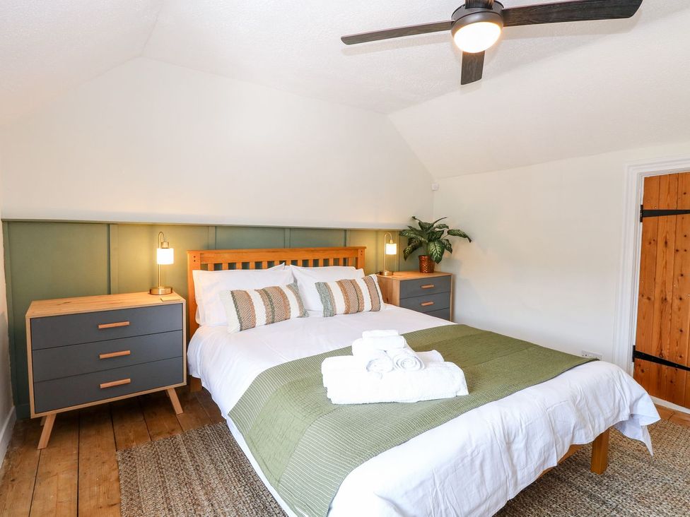 A bedroom with a bed and nightstand at Vintner's Cottage in Reedham