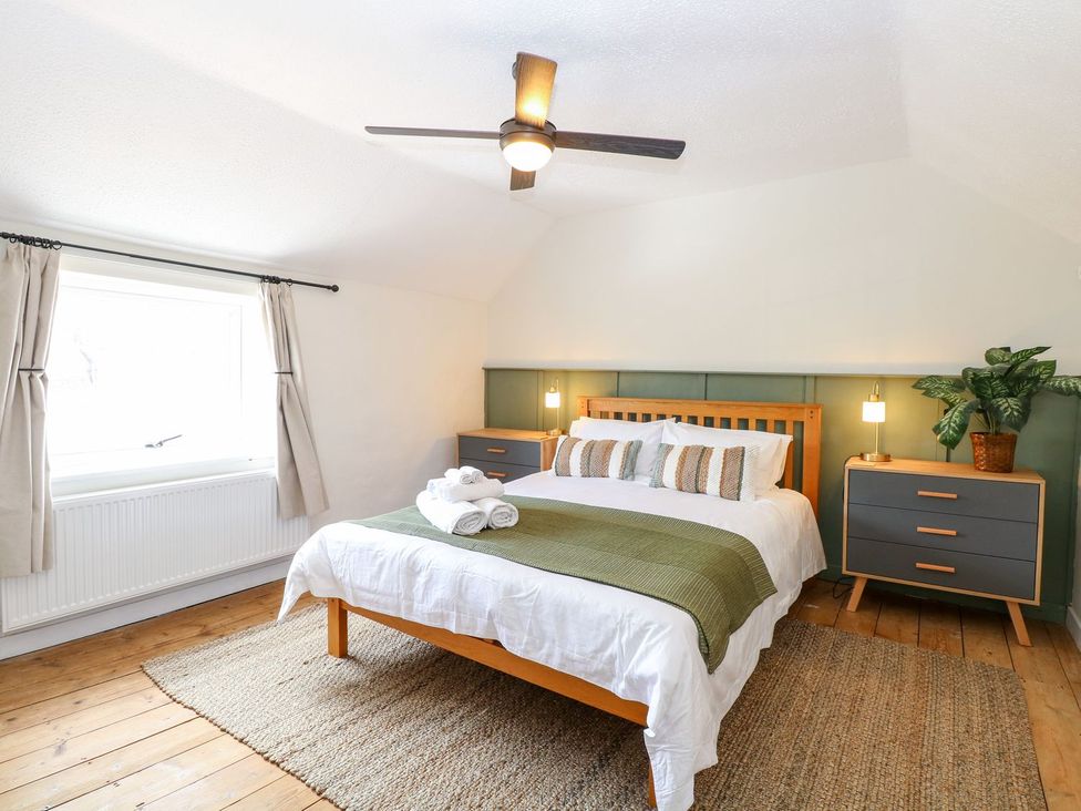 A bedroom with a bed and a nightstand at Vintner's Cottage in Reedham