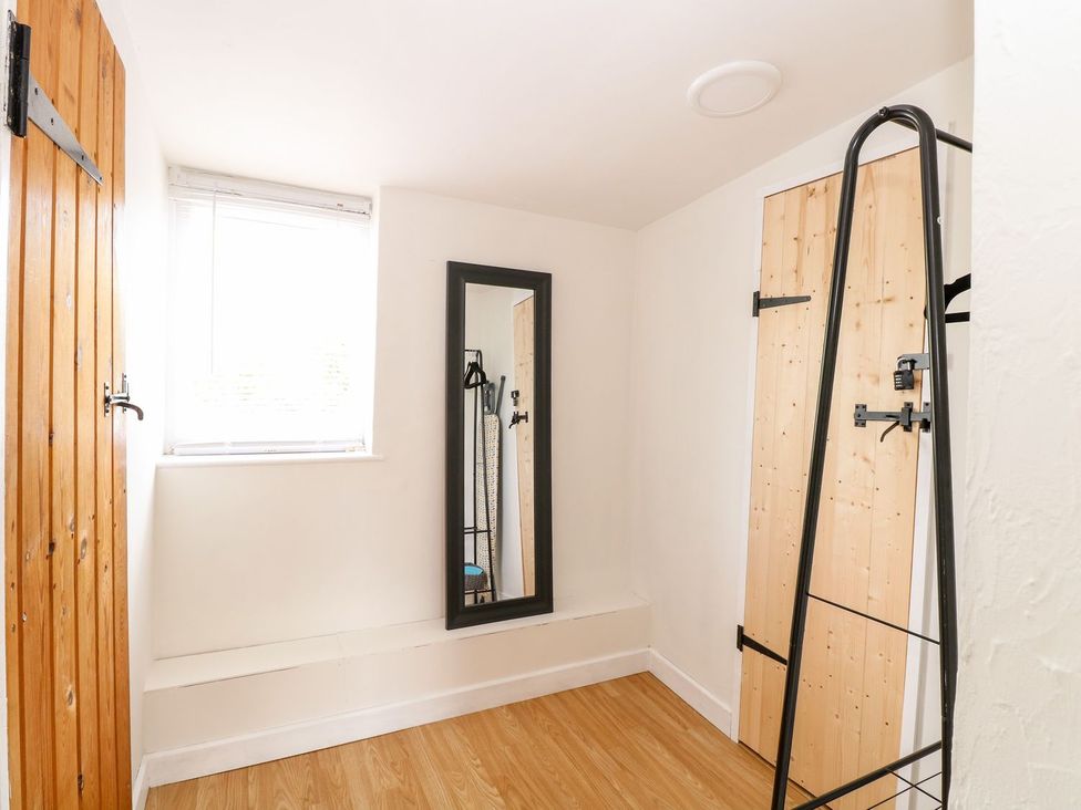 A room with a mirror and wooden door at Vintner's Cottage in Reedham