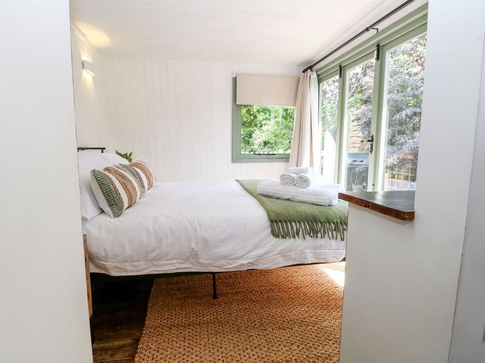 A bedroom with a bed and window at Vintner's Cottage in Reedham