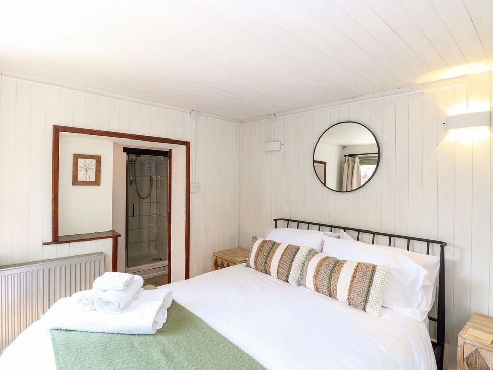 A bedroom with a bed and shower at Vintner's Cottage in Reedham