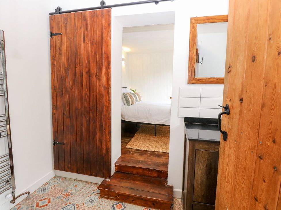 A bathroom with a sliding door and wooden steps at Vintner's Cottage in Reedham