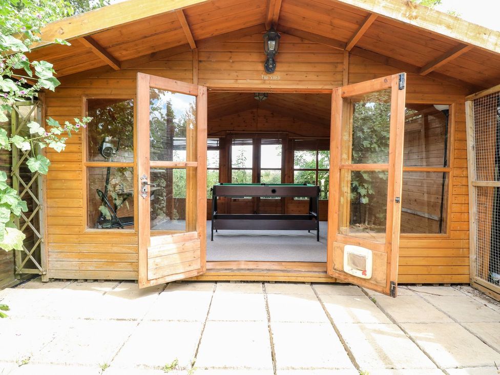 A garden room with wooden structure and double doors at Vintner's Cottage in Reedham
