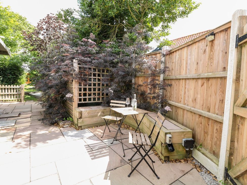 A garden with a table and chairs surrounded by plants at Vintner's Cottage in Reedham