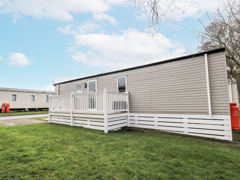 A mobile home with a deck in an outdoor area at Hadrian's Rest in Wigton