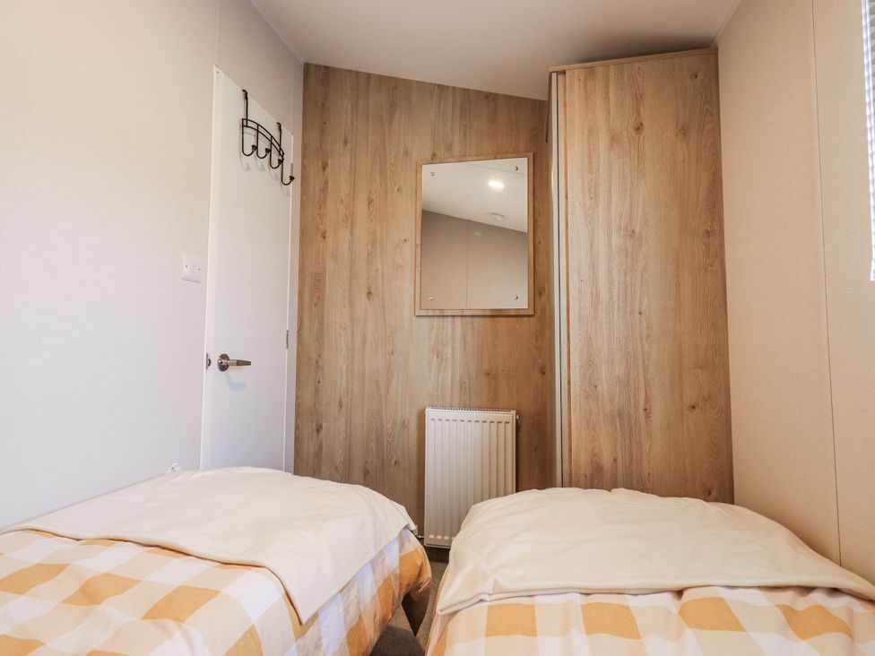 A bedroom with two beds and a mirror at Hadrian's Rest in Wigton