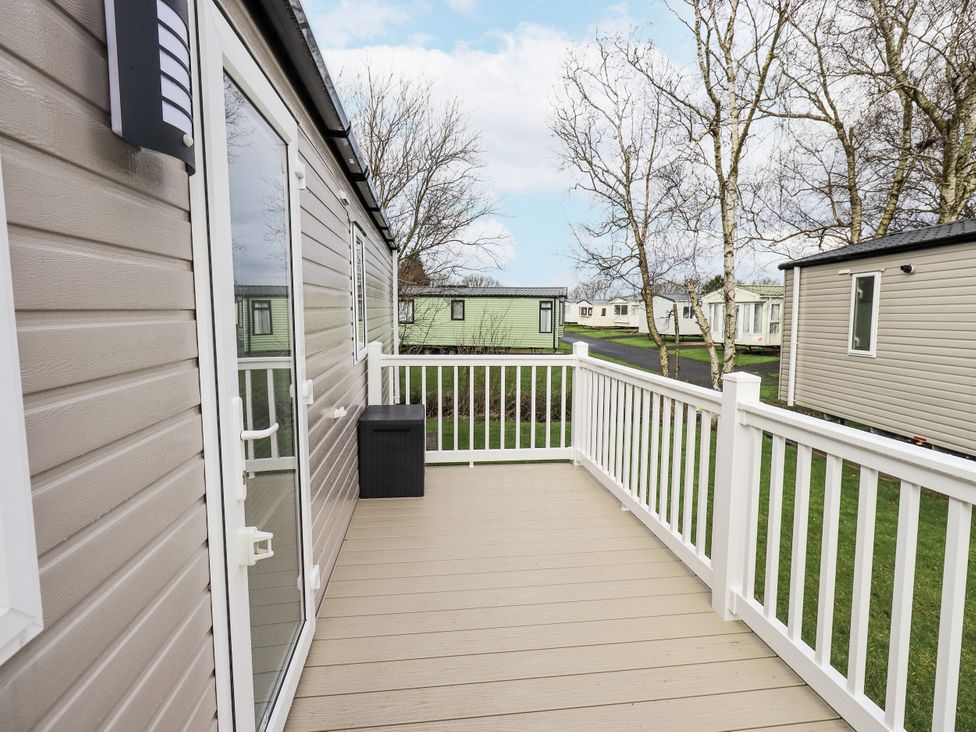 An outdoor decking area with a railing and storage box at Hadrian's Rest in Wigton