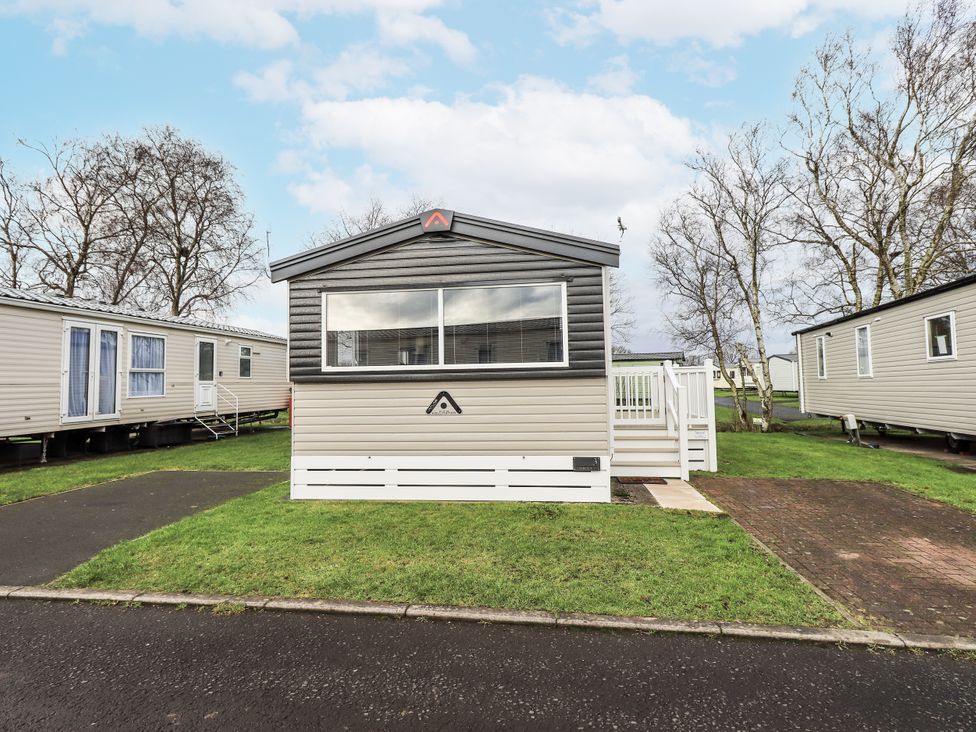 A mobile home with steps and grass outside at Hadrian's Rest in Wigton