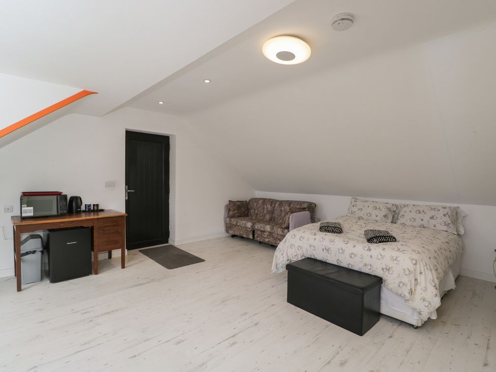 A bedroom with a bed and a sofa at The Nest in Meare near Glastonbury