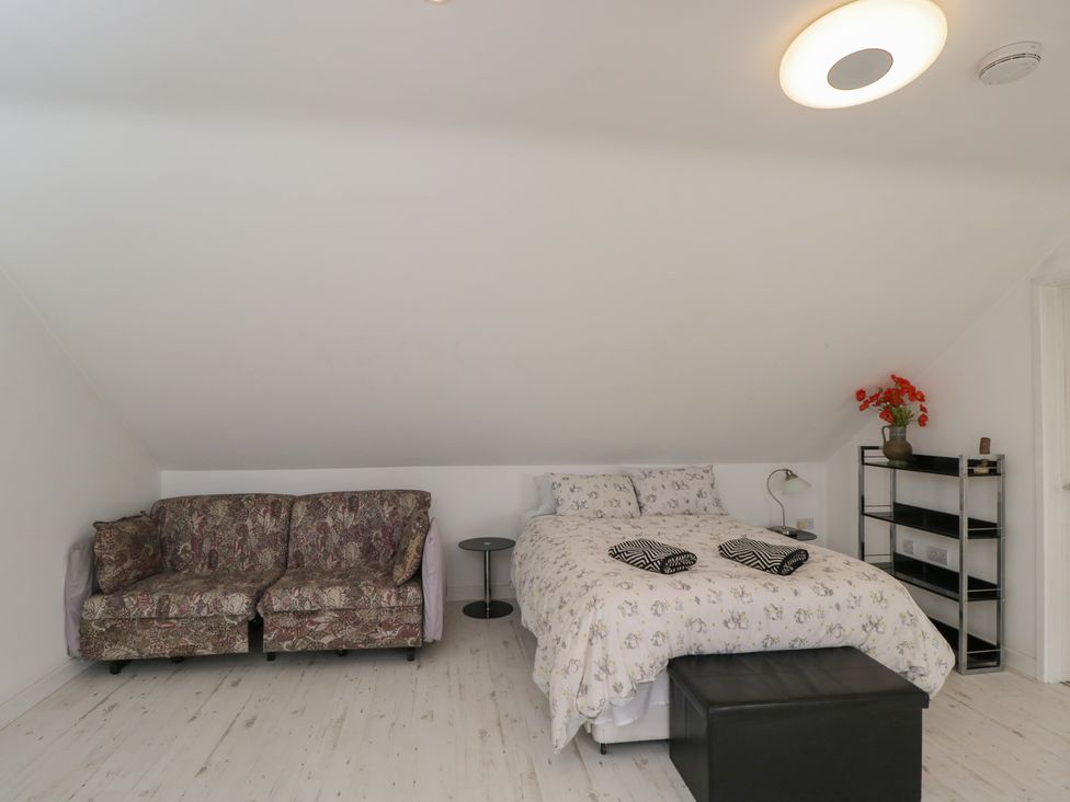 A bedroom with a bed and a sofa at The Nest in Meare near Glastonbury
