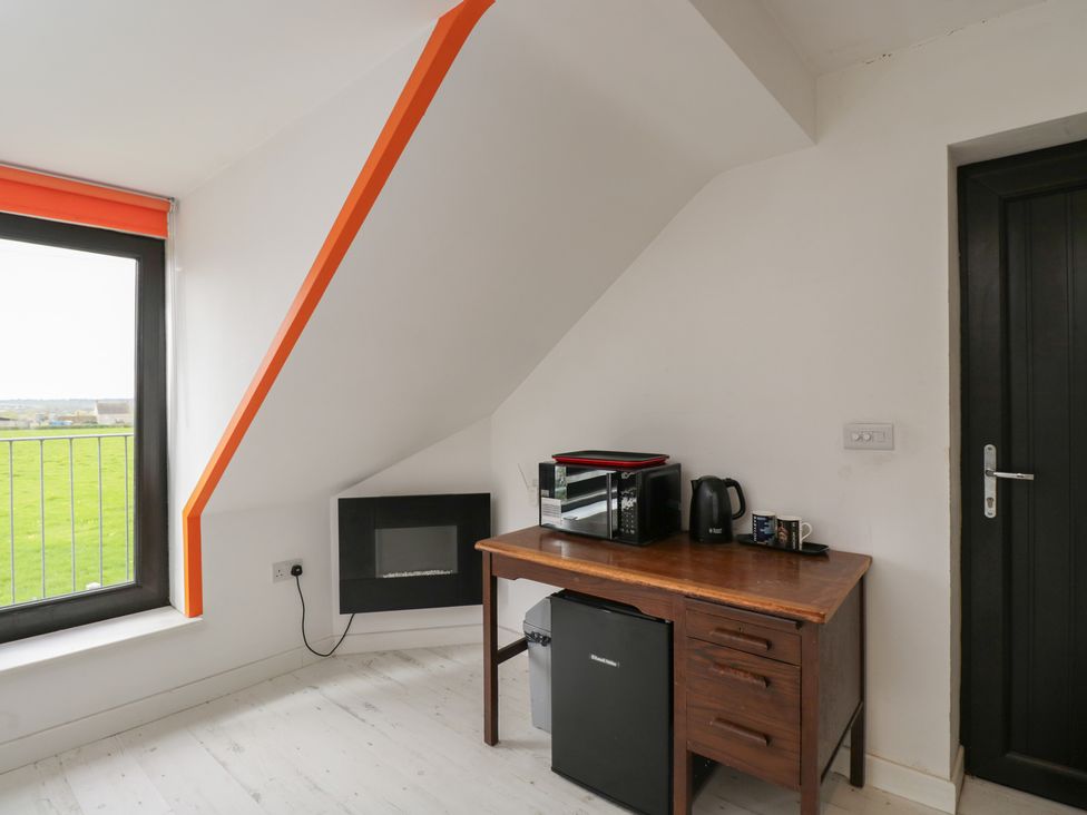 A room with a desk, microwave, kettle, and fridge at The Nest in Meare near Glastonbury