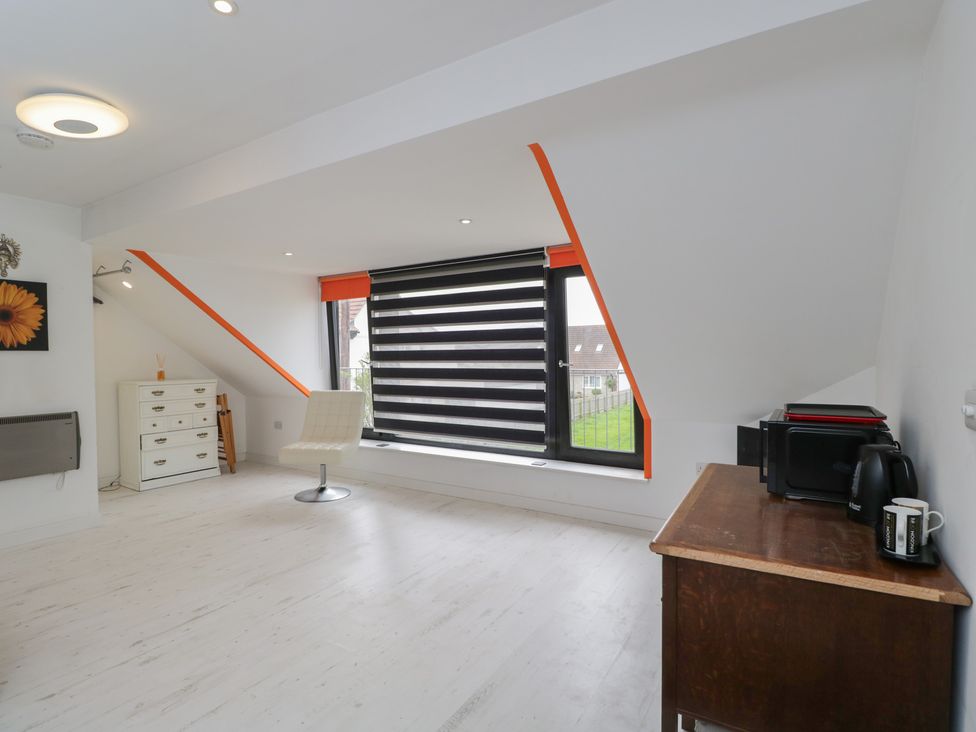 A room with a chair, table, and dresser at The Nest in Meare near Glastonbury