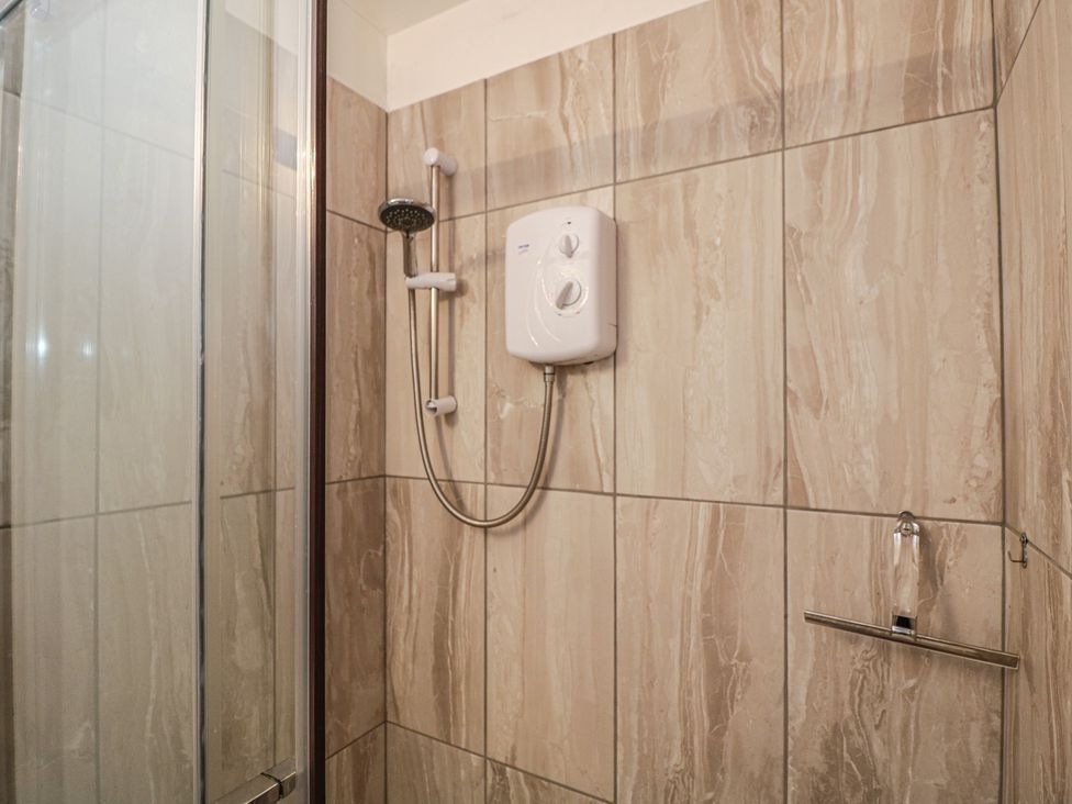 A shower with a water heater and wall tiles at The Nest in Meare near Glastonbury