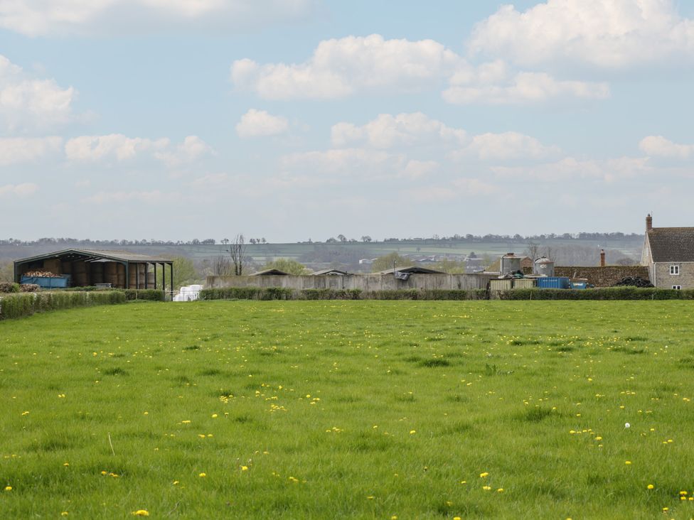 A field with sheds and houses in the distance at The Nest in Meare near Glastonbury