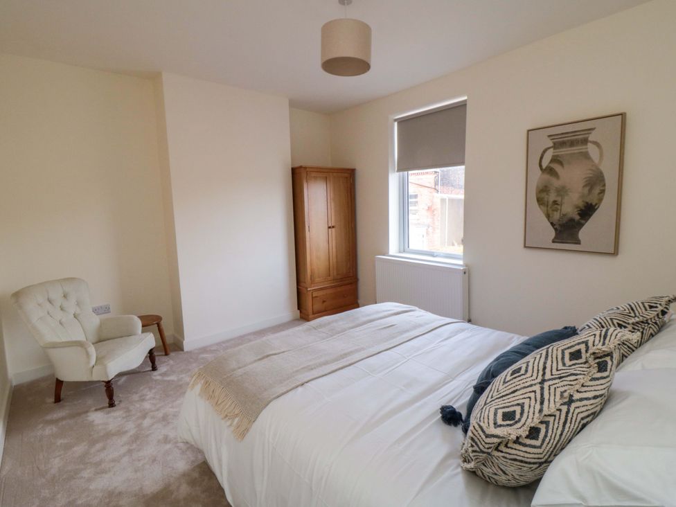 A bedroom with a bed, armchair, and wardrobe at No.9 Trafalgar St West Scarborough