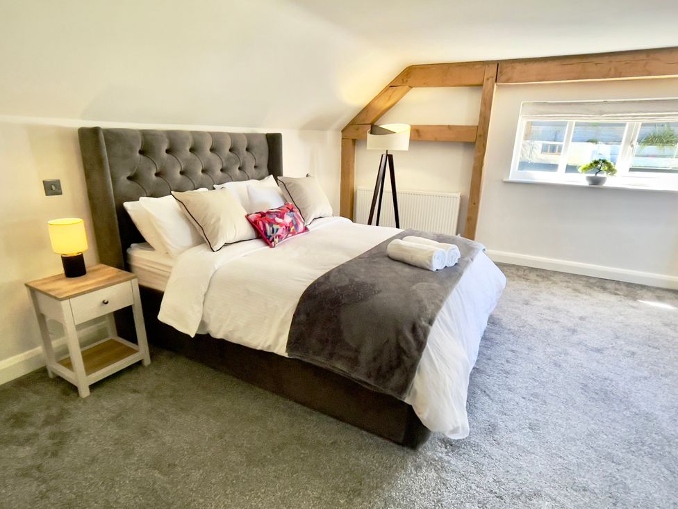 A bedroom with a bed, nightstand and window at The Oaks in Great Harwood