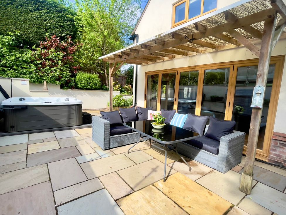 An outdoor patio with a hot tub and seating area at The Oaks in Great Harwood