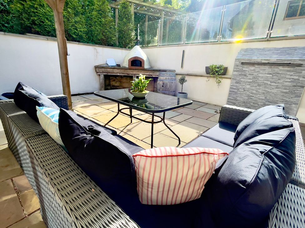 An outdoor patio with a sofa, coffee table, and outdoor oven at The Oaks in Great Harwood