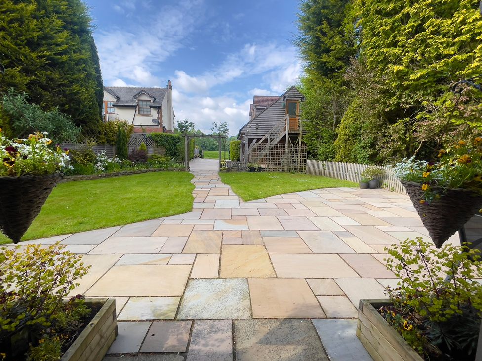 A garden with a paved pathway and flower pots at The Oaks in Great Harwood