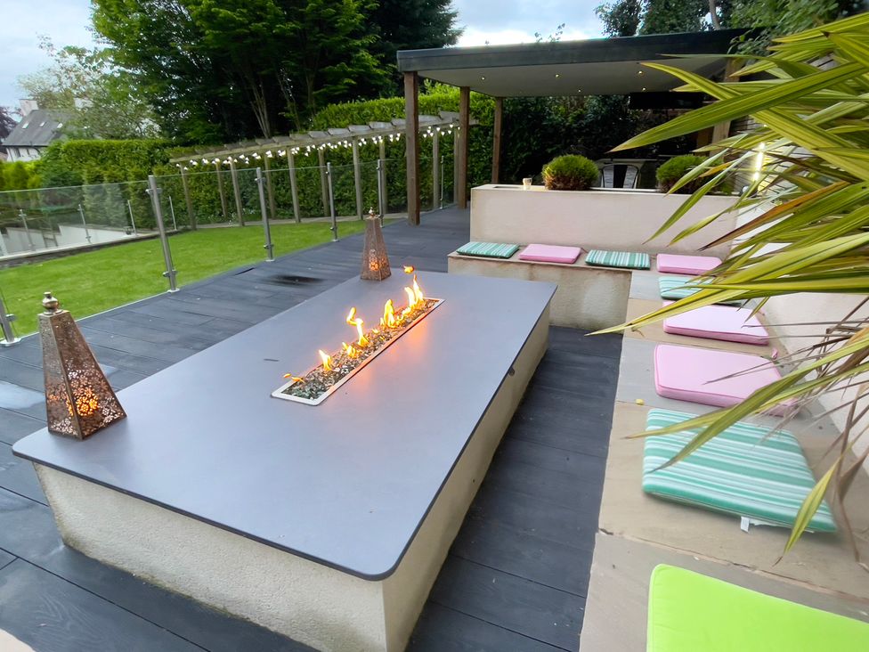 An outdoor patio with a fire pit and seating at The Oaks in Great Harwood
