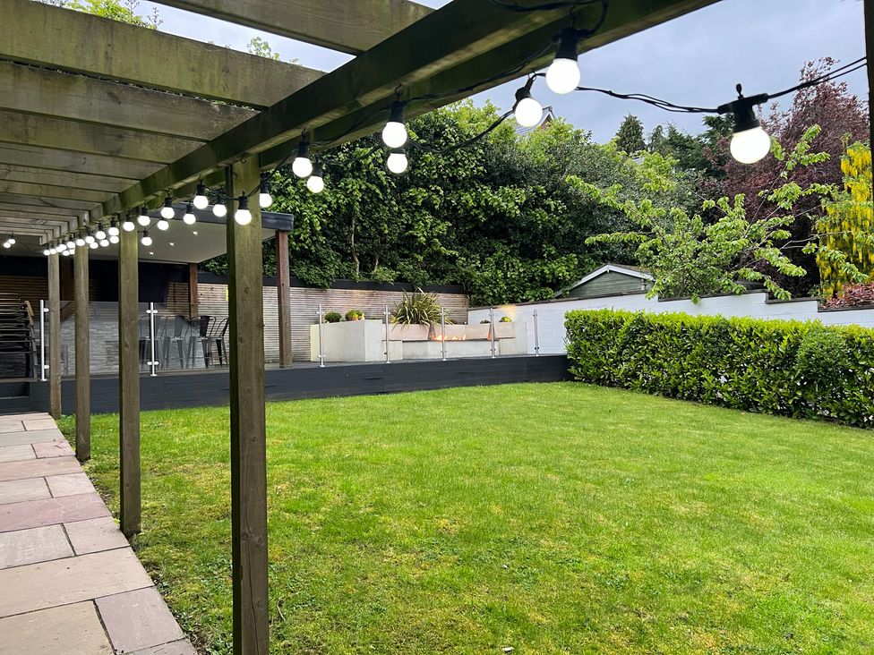 A garden with a wooden pergola and lawn at The Oaks in Great Harwood