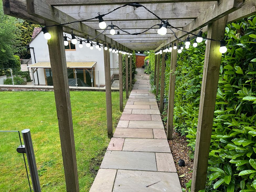 A pathway under a wooden structure with garden lights at The Oaks in Great Harwood