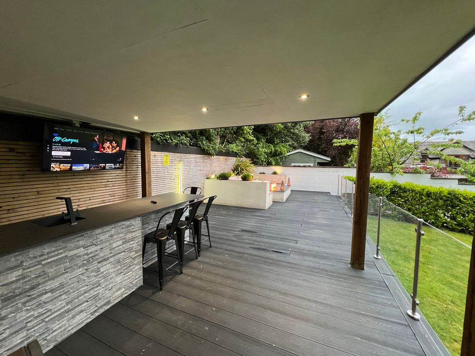 An outdoor area with a bar, stools, and a television at The Oaks in Great Harwood