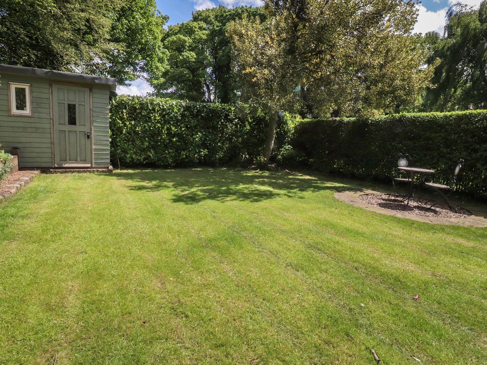 A garden with a shed and a table with chairs at 47 Grape Lane in Croston