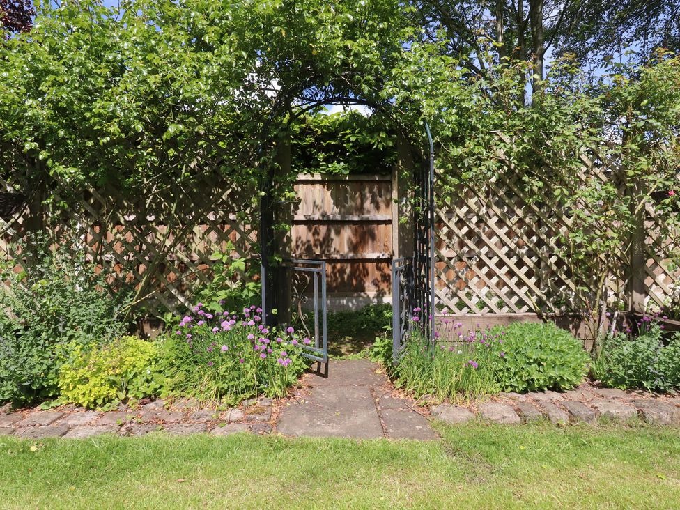 A garden with a gate and flowers at 47 Grape Lane in Croston