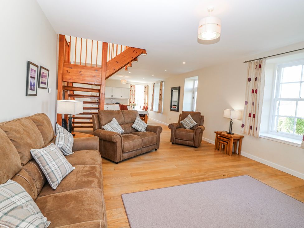 A living room with sofa and stairs at Meadowgreen Farmhouse in Forfar