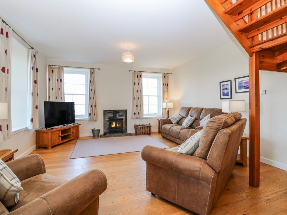 A living room with a sofa and fireplace at Meadowgreen Farmhouse in Forfar