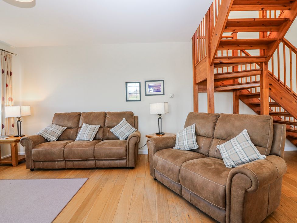 A living room with two sofas and a staircase at Meadowgreen Farmhouse in Forfar