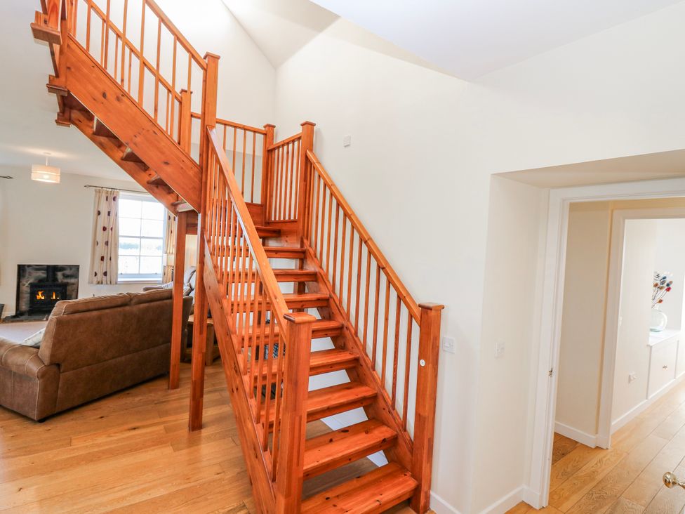 A living room with a staircase and fireplace at Meadowgreen Farmhouse Forfar