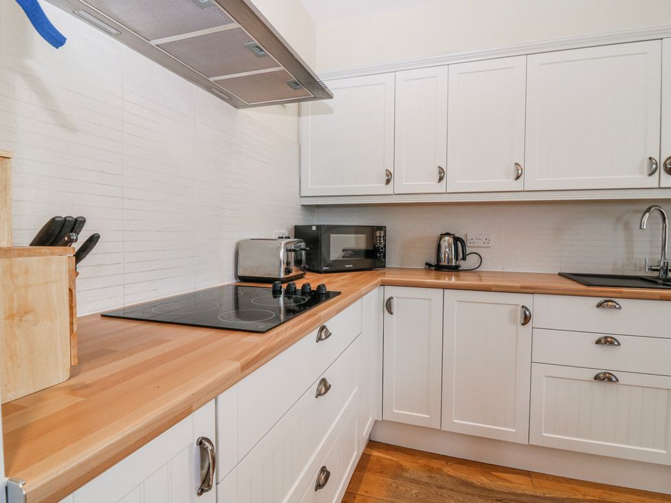 A kitchen with appliances and wooden cabinets at Meadowgreen Farmhouse in Forfar