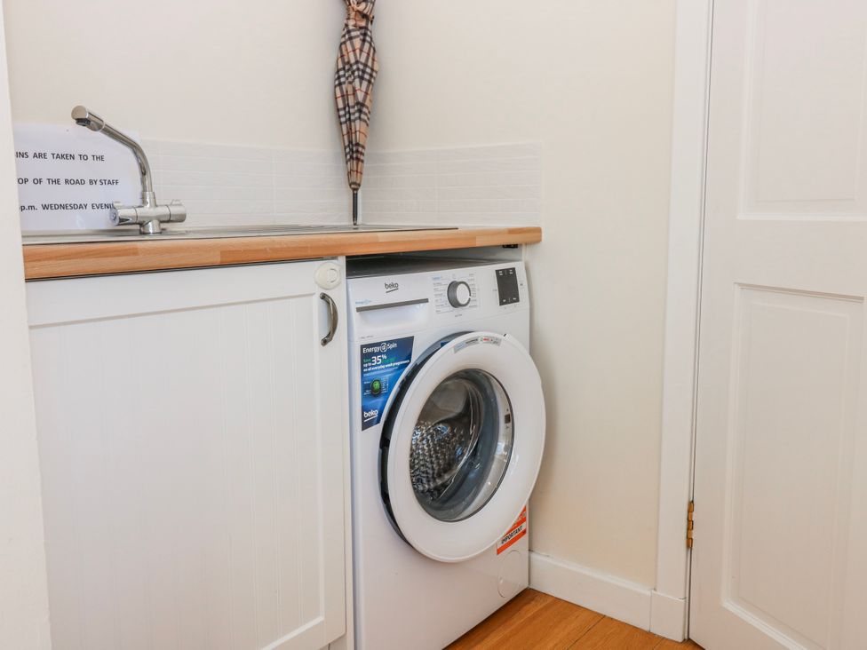 A utility room with a washing machine and sink at Meadowgreen Farmhouse Forfar