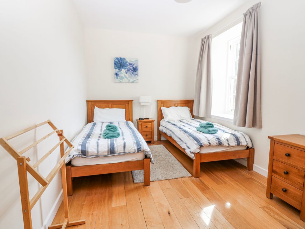 A bedroom with two beds and a clothes rack at Meadowgreen Farmhouse Forfar