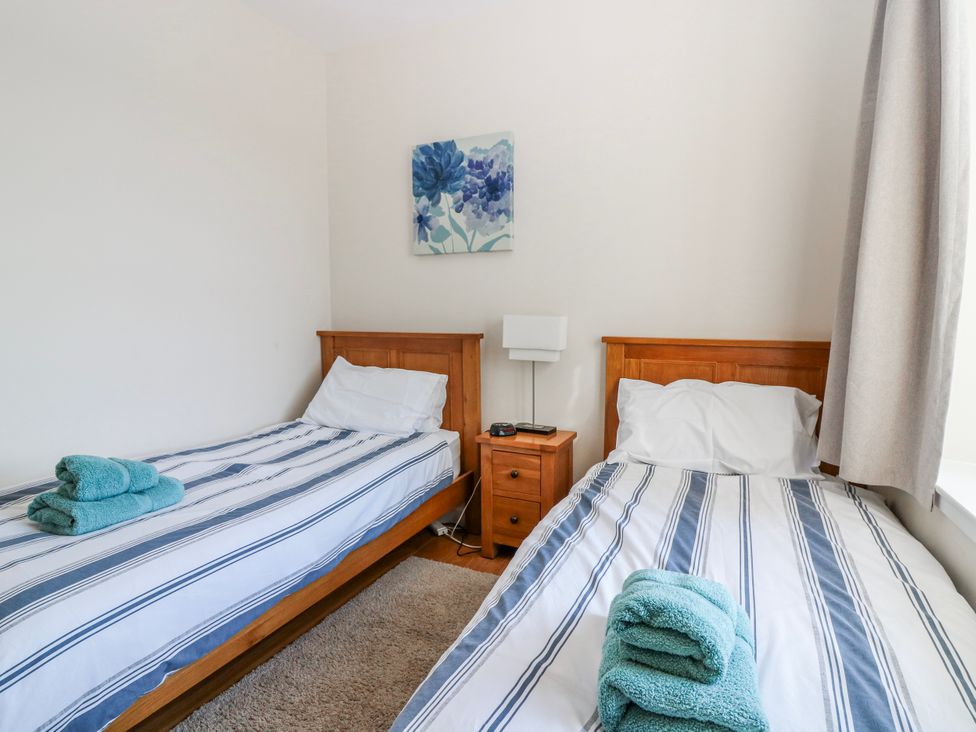 A bedroom with two beds and a nightstand at Meadowgreen Farmhouse in Forfar