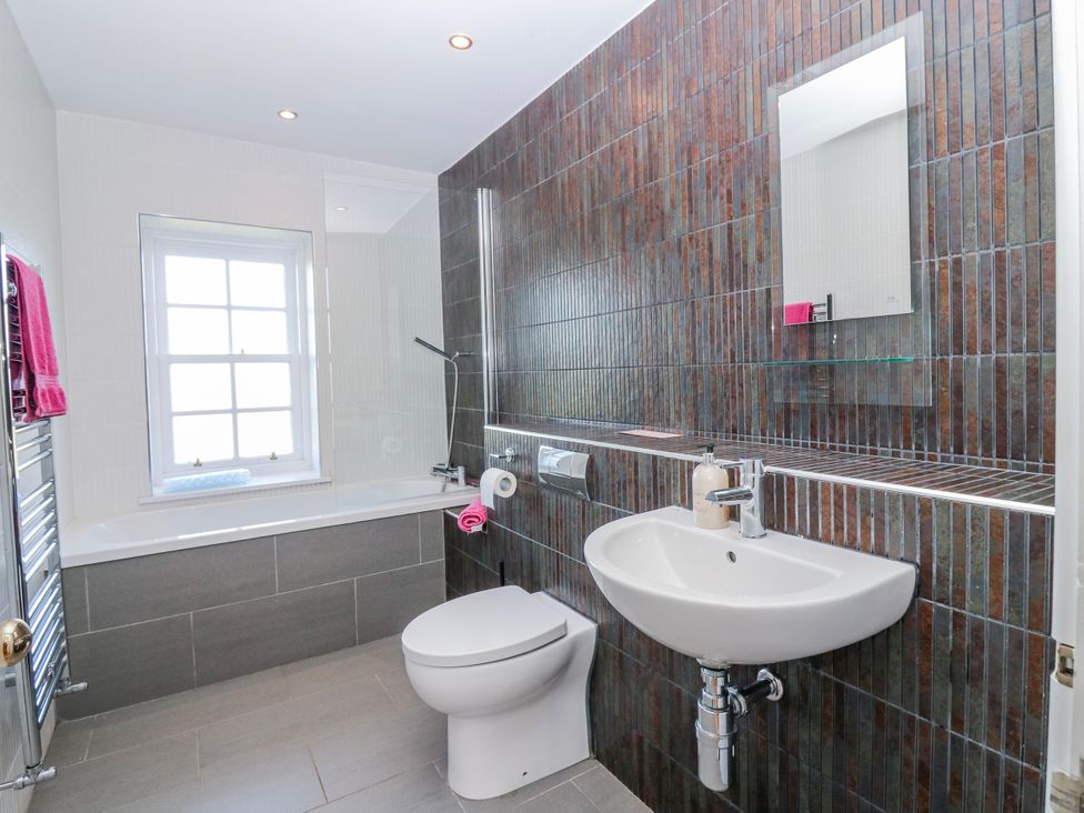 A bathroom with a bathtub, toilet, sink and mirror at Meadowgreen Farmhouse in Forfar