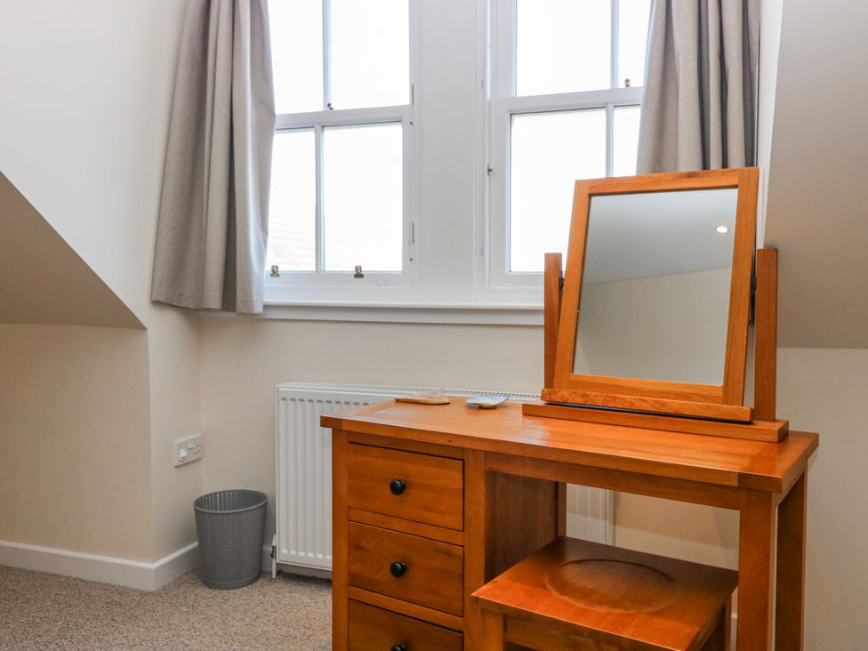 A bedroom with a dressing table and mirror at Meadowgreen Farmhouse, Forfar