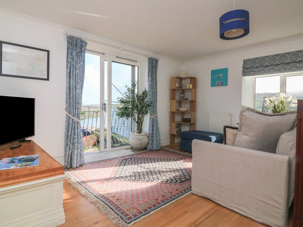 A living room with a television, sofa, and bookshelf at 4 The Elms in Salcombe