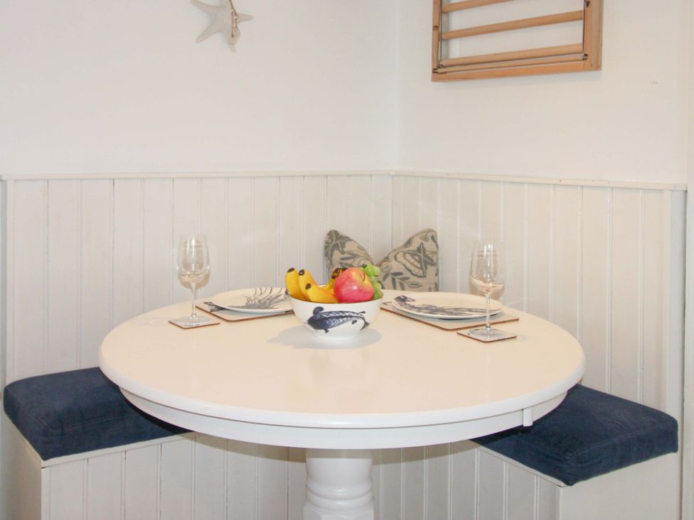 A dining area with a round table and fruit bowl at 4 The Elms in Salcombe