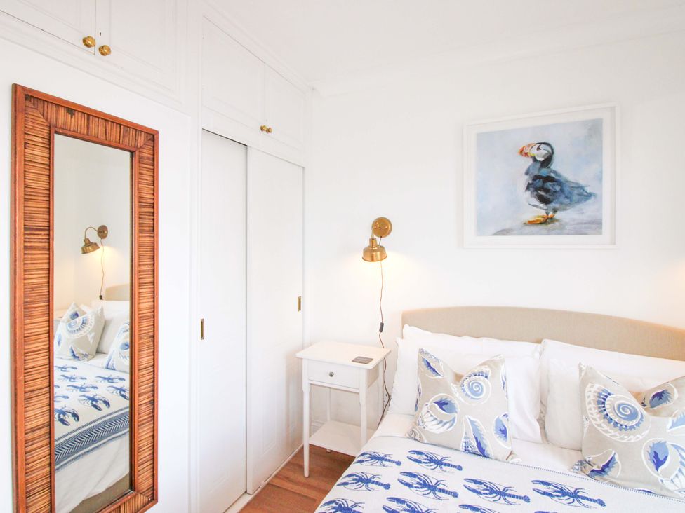 A bedroom with a bed and a mirror at 4 The Elms in Salcombe