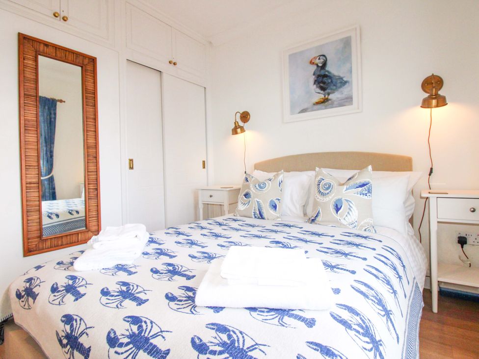 A bedroom with a bed and a mirror at 4 The Elms Salcombe